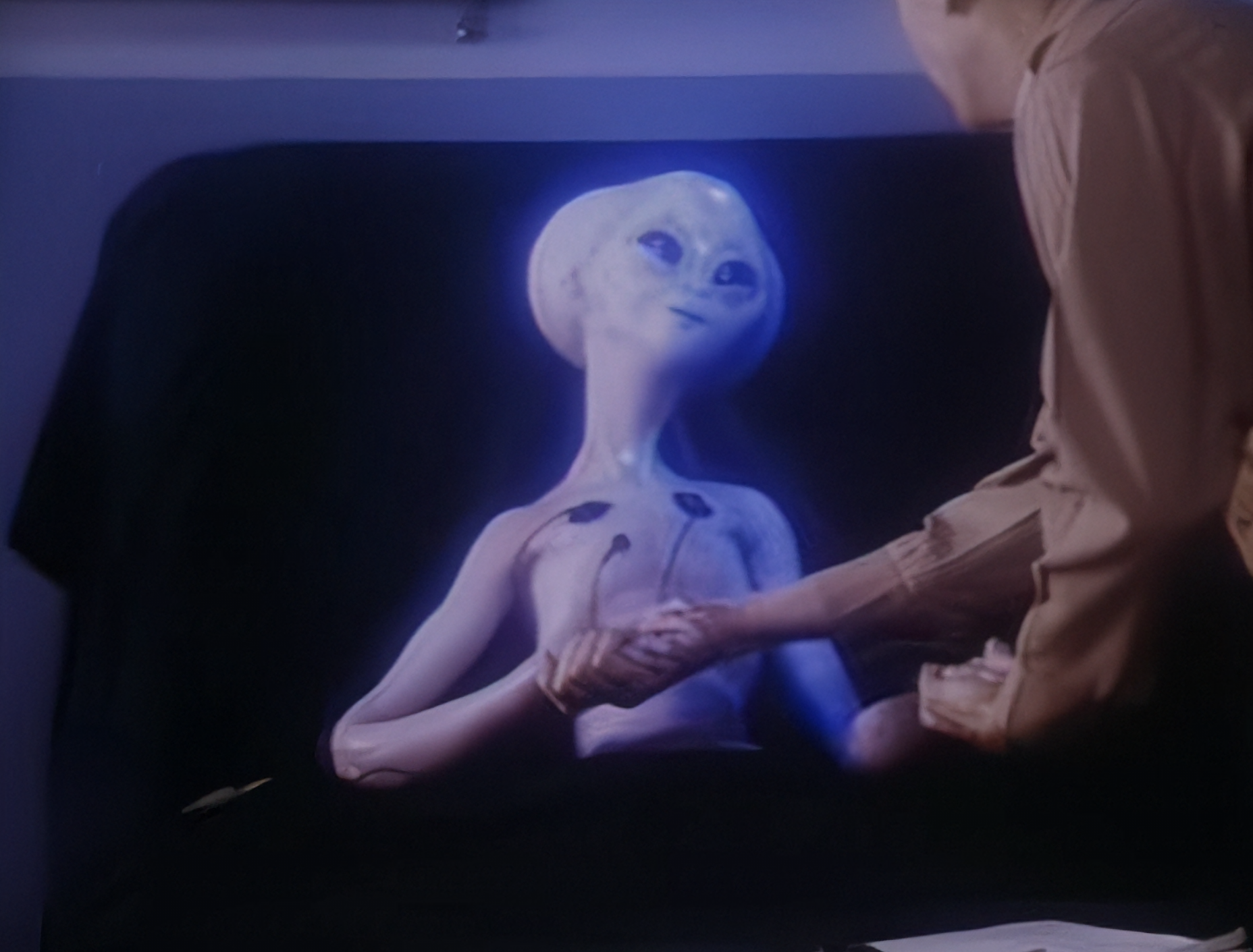 Kaader filmist Roswell: The U.F.O. Cover-Up, kus inimene surub kätt halli olendiga